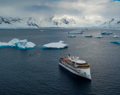Crucero navegando entre icebergs frente a costas nevadas