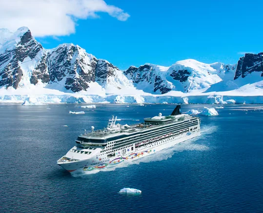 Crucero navegando entre montañas nevadas y hielos australes