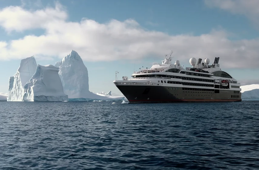 Buque de expedición navegando junto a un iceberg en la Antártida